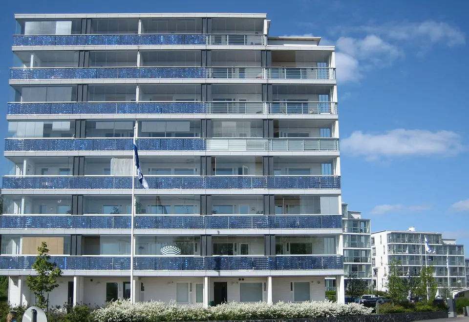 Çok katlı bir apartmanın balkon korkuluklarına entegre edilmiş mavi güneş panelleri