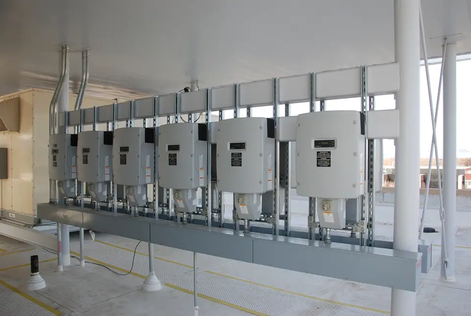 Bir binada duvara yan yana monte edilmiş altı dizi inverter ve kablo kanalları