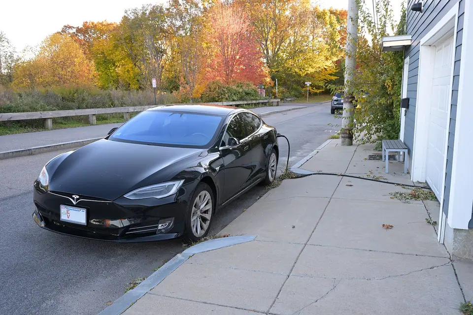 Bir evin önünde kaldırıma park etmiş, kabloyla evden şarj edilen elektrikli otomobil